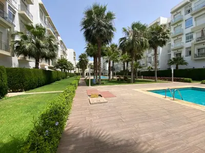 a walkway with palm trees and a swimming pool at Appartement de haut standing,4 piscines in Bouznika
