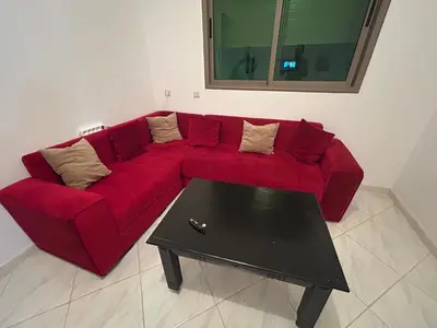 a red couch in a living room with a coffee table at Appartement meublé calme et chaleureuse in Temara