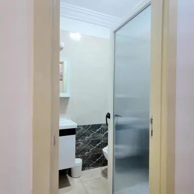 a bathroom with a glass shower door and a sink at Appartement Sidi Rahal Casablanca - proche du SHEMPARK payant, Sidi rahal et tamaris plage in Sidi Rahal