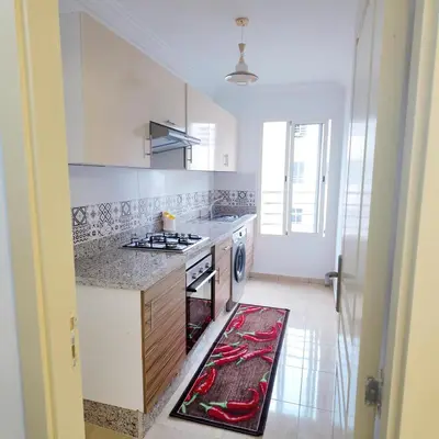 a white kitchen with a stove and a sink at Appartement Sidi Rahal Casablanca - proche du SHEMPARK payant, Sidi rahal et tamaris plage in Sidi Rahal