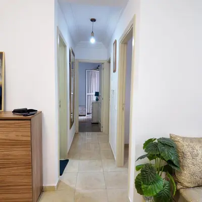 a hallway with a couch and a plant in a room at Appartement Sidi Rahal Casablanca - proche du SHEMPARK payant, Sidi rahal et tamaris plage in Sidi Rahal