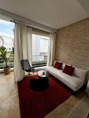 a living room with a white couch and a red rug at Les Perles de Tamaris Beach access Pools in Casablanca