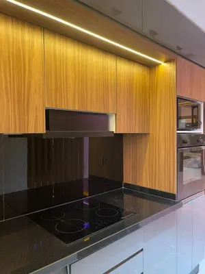 a kitchen with a black counter top and wooden cabinets at Appartement Luxueux Mer & Piscine in Mansouria