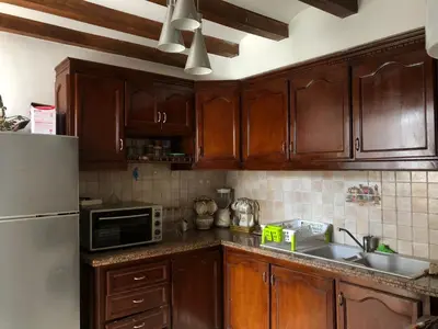 a kitchen with wooden cabinets and a sink and a refrigerator at Appartement à Garden Beach , Sidi Rahal in Sidi Rahal