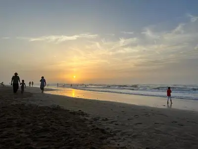 a group of people walking on the beach at sunset at Appartement à Garden Beach , Sidi Rahal in Sidi Rahal