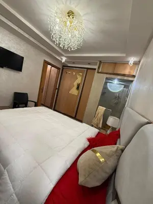 a bedroom with a large white bed with a chandelier at Comfortable apartment temara in Temara