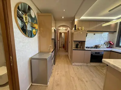 a kitchen with white cabinets and a large clock on the wall at Comfortable apartment temara in Temara