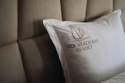 a white pillow on a bed with a black breakfast ban record at Luxury Villa Jack Beach Resort Pool & Seaview in Tamaris