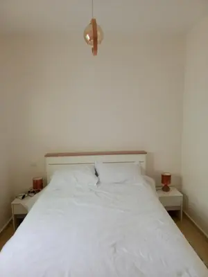 a bedroom with a white bed with two night stands at Appartement neuf, propre et ensoleillé in Temara