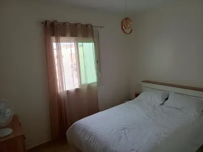 a bedroom with a white bed and a window at Appartement neuf, propre et ensoleillé in Temara