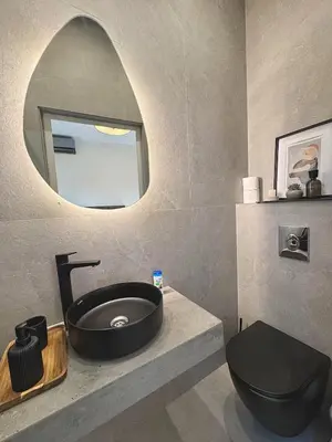 a bathroom with a black toilet and a round mirror at private villa with swimming pool in Rabat