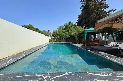 a swimming pool next to a white wall and a house at private villa with swimming pool in Rabat