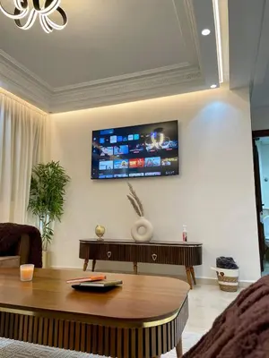 a living room with a table and a tv on the wall at Appartement chic - Princesses in Casablanca