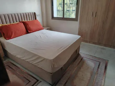 a bed with red pillows on it in a room at Charmant appartement à Casablanca Près tram & gare in Casablanca