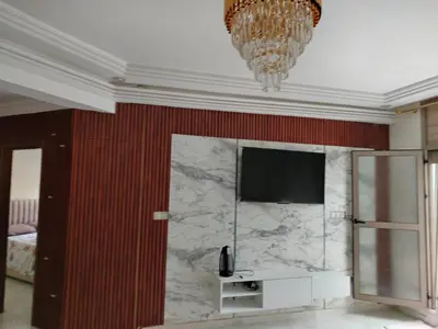 a room with a television and a marble wall at Charmant appartement à Casablanca Près tram & gare in Casablanca