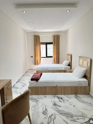 a room with two beds and a chair in it at Rabat Agdal apartment in Rabat