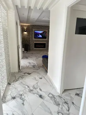 a hallway with marble flooring and a television on a wall at Rabat Agdal apartment in Rabat