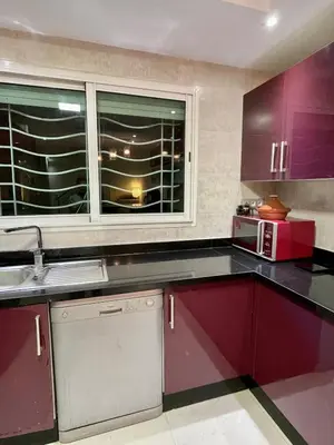 a kitchen with purple cabinets and a microwave and a window at 2-bedroom duplex for rent in Temara