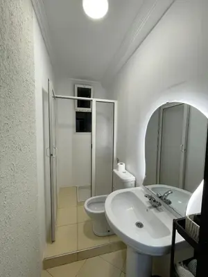 a white bathroom with a sink and a toilet at 2-bedroom duplex for rent in Temara