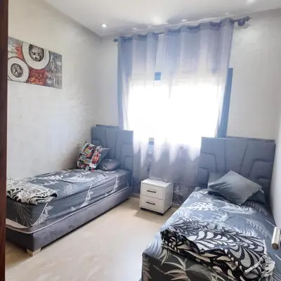 a bedroom with two twin beds and a window at Appartement Tamaris avec piscine et plage privée in Casablanca