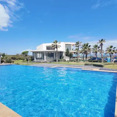 a large swimming pool in front of a house at Appartement Tamaris avec piscine et plage privée in Casablanca