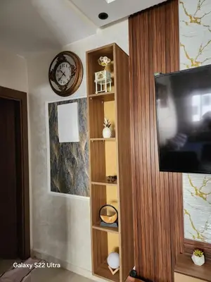 a living room with a tv and a wooden book shelf at Appartement ainsbaa in Casablanca