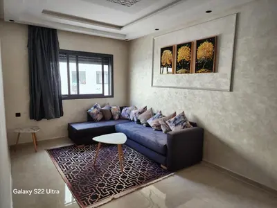 a living room with a blue couch and a rug at Appartement ainsbaa in Casablanca