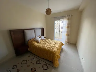 a bedroom with a bed with a yellow blanket on it at Magnifique Appartement Bahia Golf Beach in Bouznika