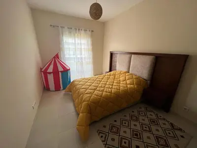 a bedroom with a bed with a yellow comforter and a window at Magnifique Appartement Bahia Golf Beach in Bouznika