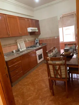 a kitchen with wooden cabinets and a table and a stove at Bouznika 100m2 Piscineplage in Bouznika