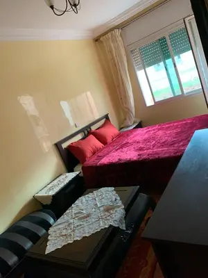 a bedroom with a bed and a couch and a window at Bouznika 100m2 Piscineplage in Bouznika