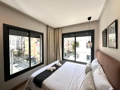 a bedroom with a bed and two large windows at NESK STAY Gauthier in Casablanca