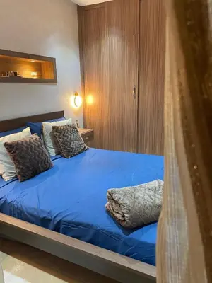 a bedroom with a bed with blue sheets and pillows at Beautiful apartment with pool in Mansouria