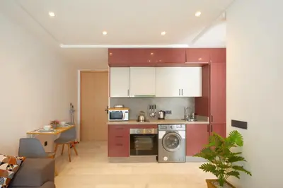 a kitchen with red cabinets and a washer at Beautiful 1 Bedroom in the Center of Casablanca in Casablanca