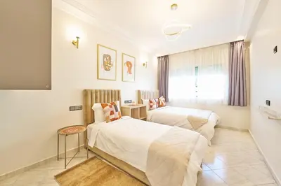 two beds in a white room with a tv at 3 Bedrooms and Room Balcony in Central Casablanca in Casablanca
