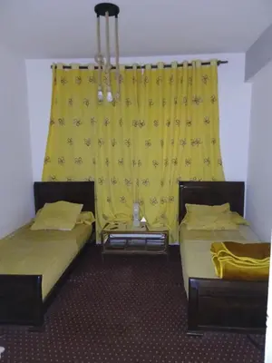 two beds in a room with a yellow curtain at Maison agdal 2 chambres salon in Rabat