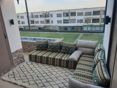a couch on a balcony with a view of a building at Sunny modern Apartment- Ocean & Pool view in Al Mansouria in Mansouria