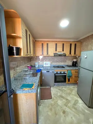 a kitchen with wooden cabinets and a white refrigerator at Sweethome in Bouznika