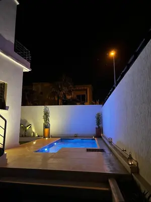 a swimming pool in a backyard at night at Modern House private Pool, Rooftop & beach view in Mohammedia