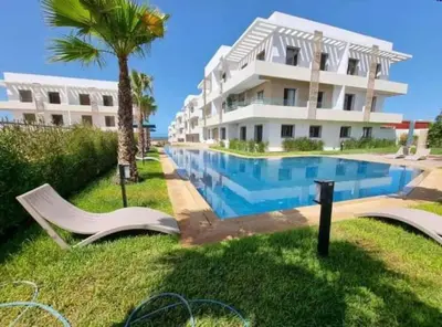 a resort with a swimming pool next to a building at Seaside escape beautiful garden apartment in Sidi Rahal