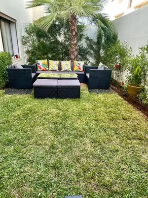 a couch sitting in the middle of a lawn at Seaside escape beautiful garden apartment in Sidi Rahal