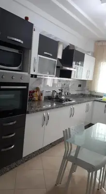 a kitchen with black and white appliances and a table at Sidi rehal in Sidi Rahal