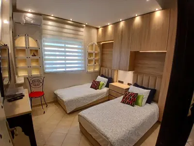 a bedroom with two beds and a desk and a window at Superbe appartement corniche in Casablanca