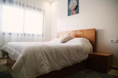 a bedroom with a bed with white sheets and a window at Studio haut standing CASA in Aïn Harrouda