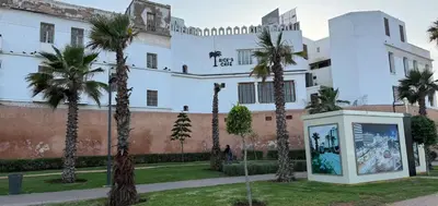 a large white building with palm trees in front of it at Charmante Maison Traditionnelle au Cœur de la Médina, 5 min de Casa Port in Casablanca
