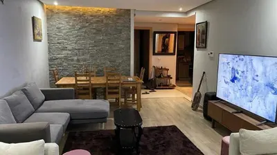 a living room with a couch and a large screen tv at Prestigia golf city bouskoura in Casablanca
