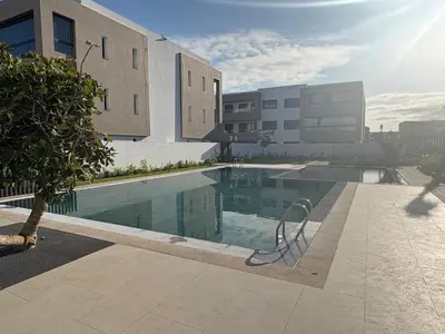 a swimming pool in front of a building at Bain de soleil à Dar Bouazza in Dar Bouazza