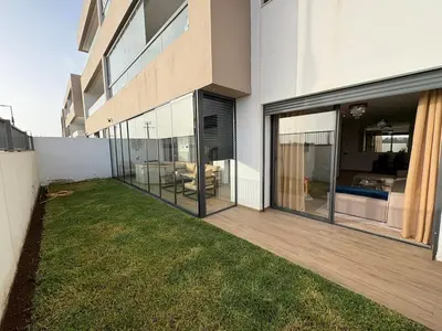 a house with glass doors and a yard at Bain de soleil à Dar Bouazza in Dar Bouazza