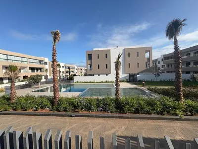 a group of palm trees in front of buildings at Bain de soleil à Dar Bouazza in Dar Bouazza
