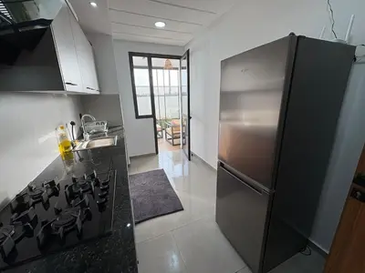 a kitchen with a stainless steel refrigerator and a stove at Bain de soleil à Dar Bouazza in Dar Bouazza
